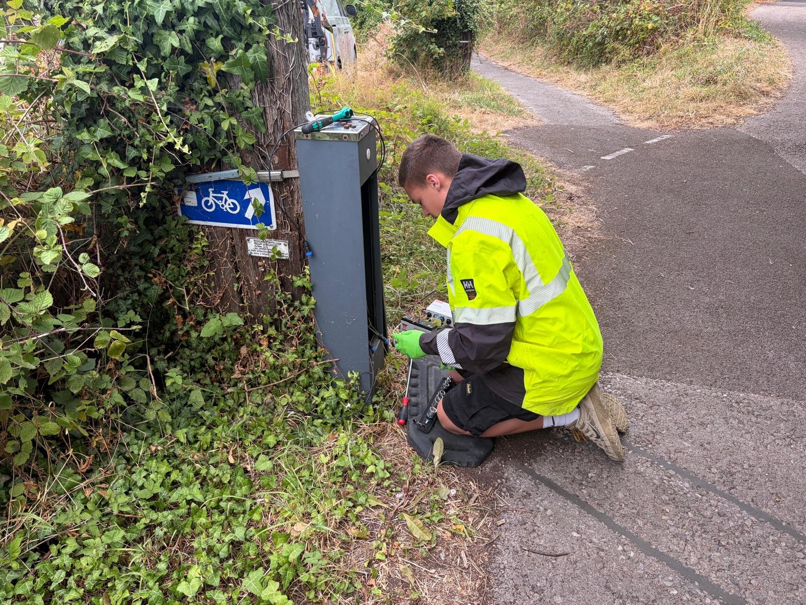 Field engineer servicing a roadside detection cabinet on a shared cycle path